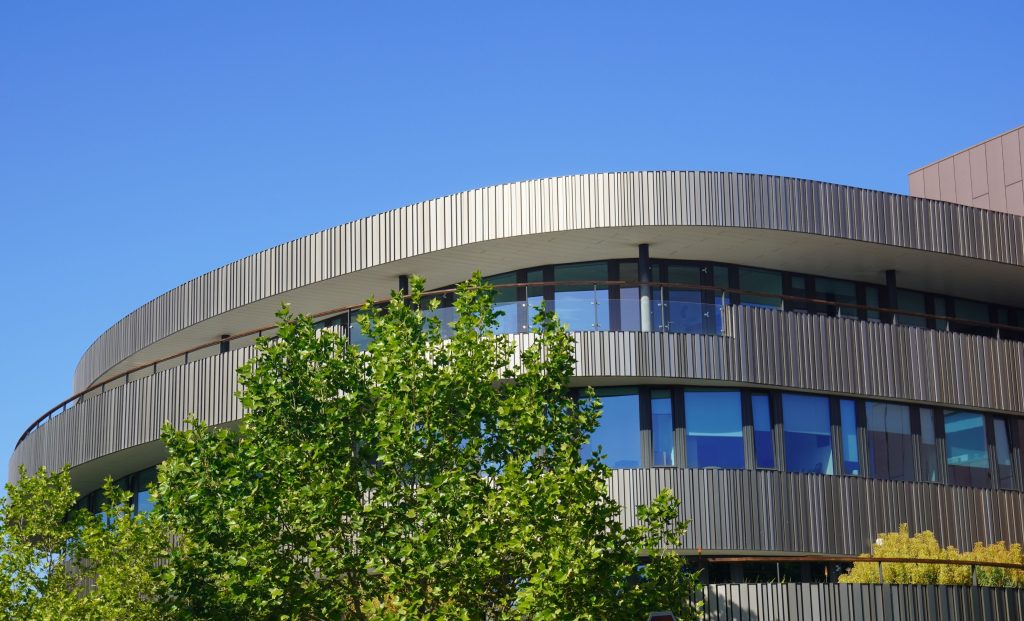 A modern circular university building under a clear blue sky.