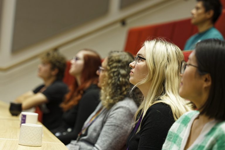 A group of students listen to a lecture.