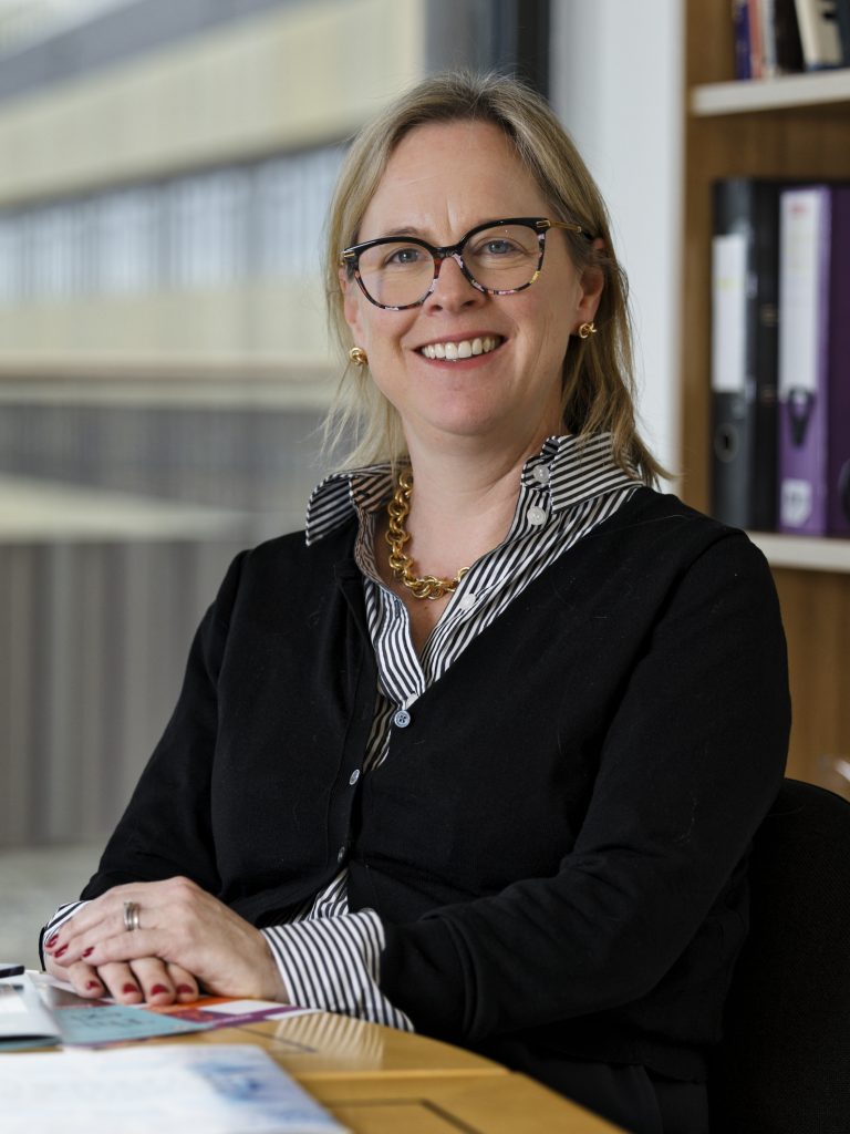 Portrait of a woman with glasses smiling towards the camera