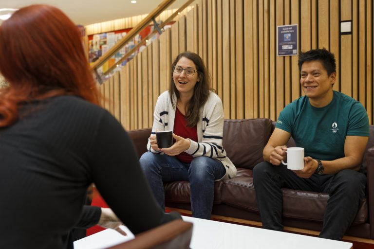 Woman and man talking top person off camera in relaxed setting with mug of hot drink.