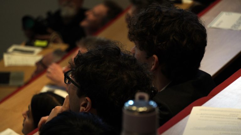 Two young people watch and listen to a lecture.