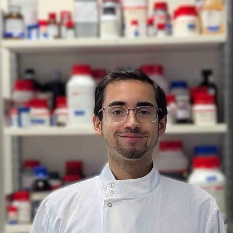 Portrait of a man in a lab coat. A lab environment forms the background.