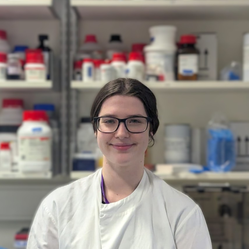 Portrait of a woman in a lab coat. Lab environment forms the background.