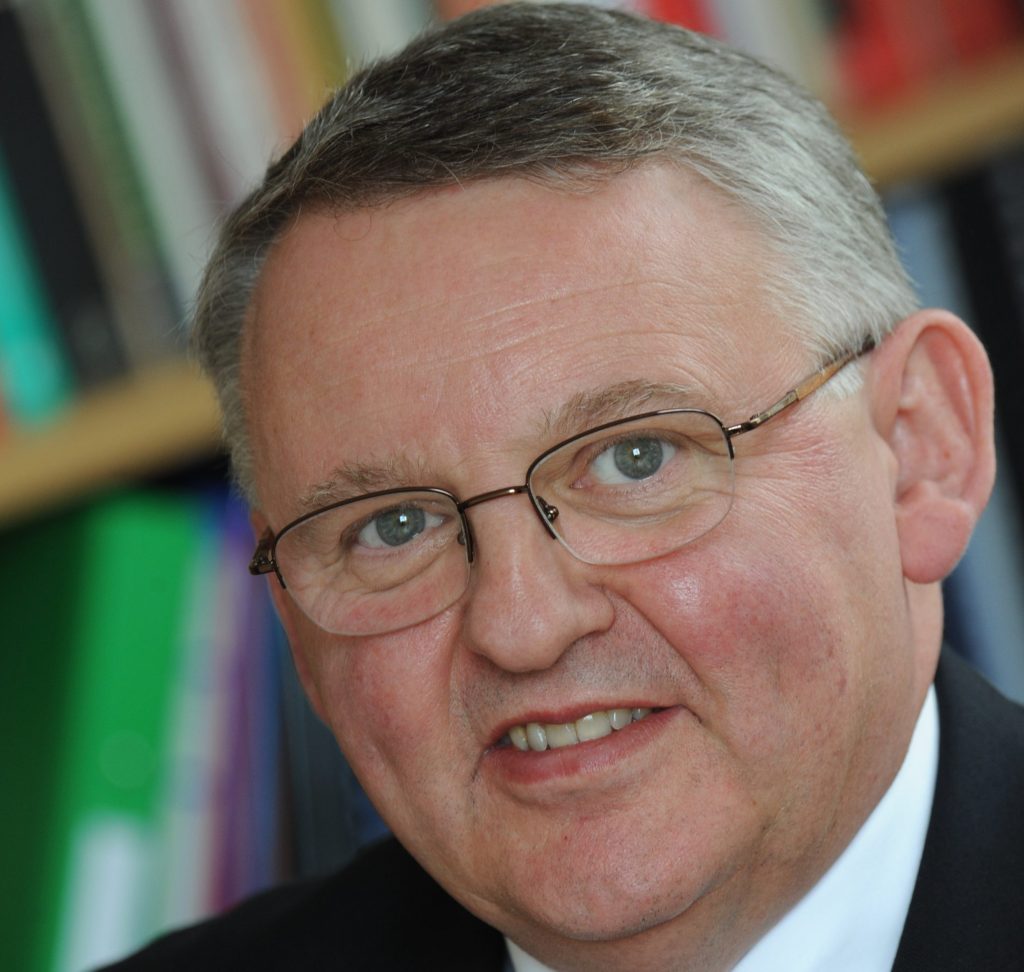 A portrait of a man with glasses looking towards the camera.