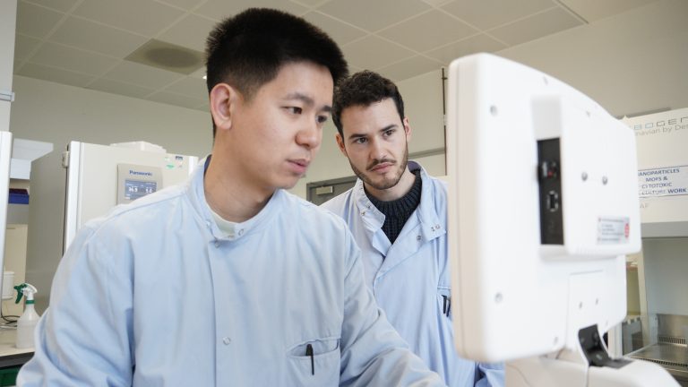 Two scientists look at a computer screen in a laboratory