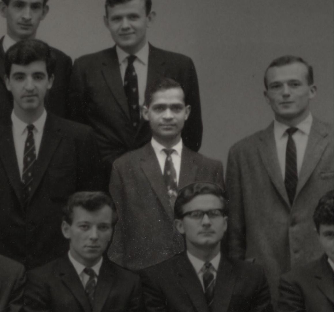 A black and white image of seven men. The central man is highlighted