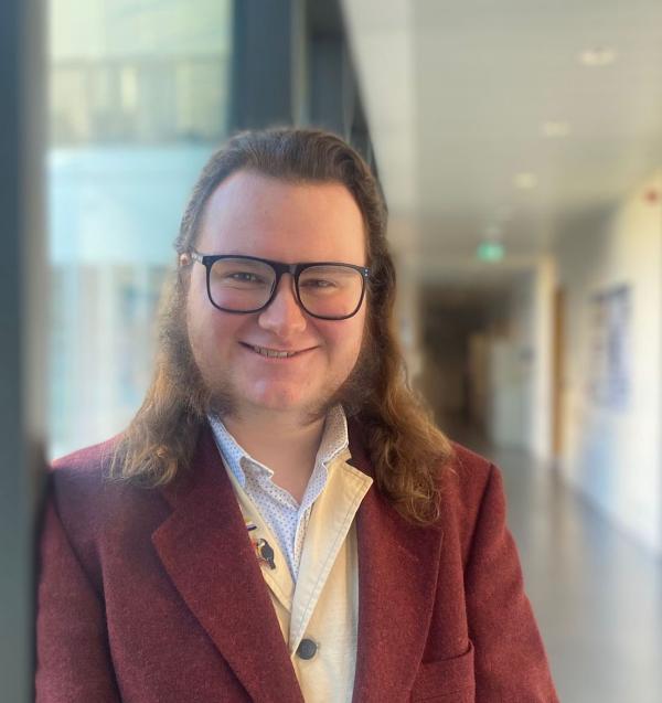 Portrait of a long-haired man in a laboratory corridor.