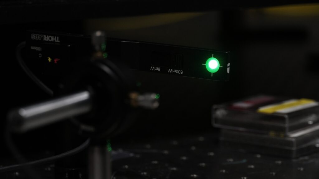 Close up of a green laser light in the dark.
