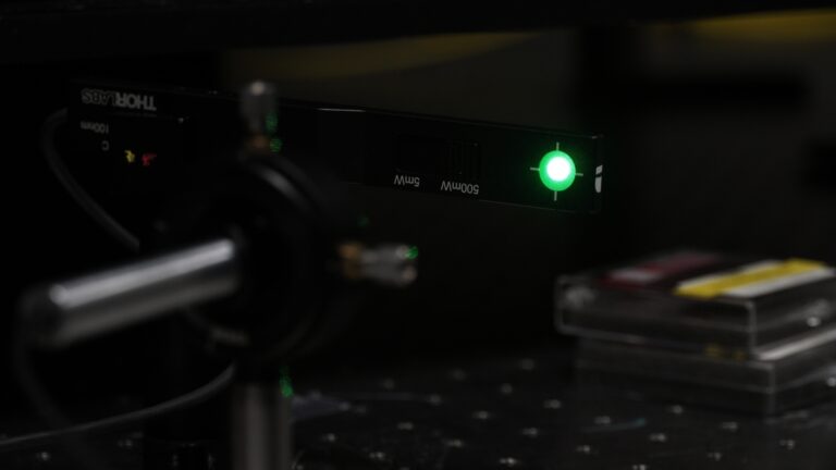 Close up of a green laser light in the dark.