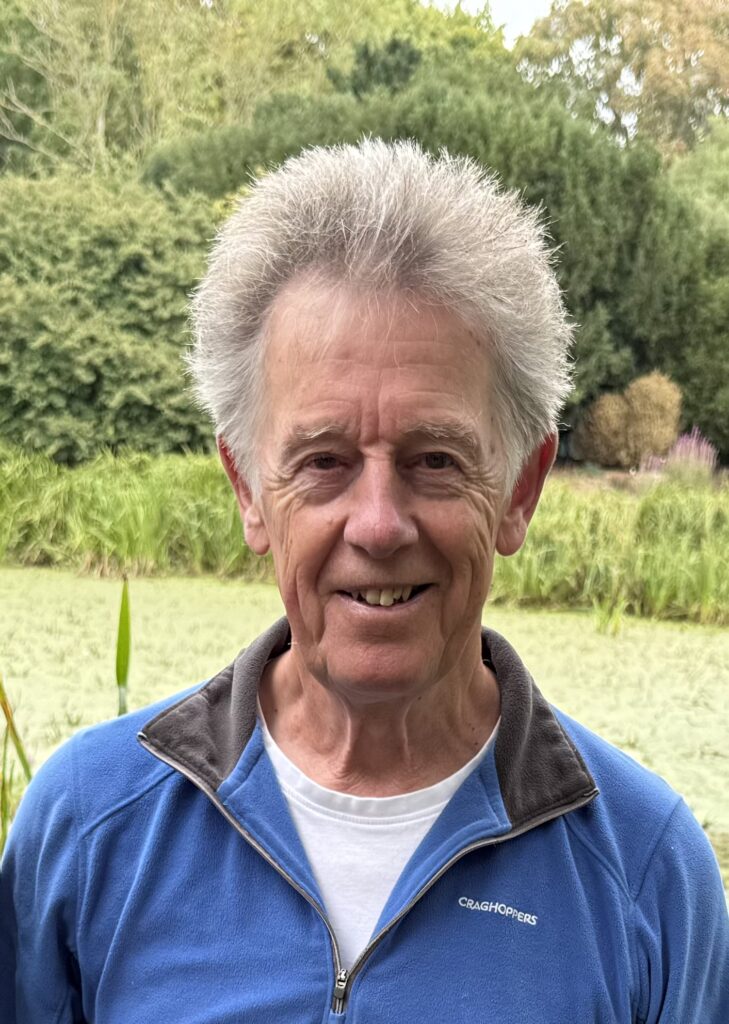A man in a blue jacket smiles for the camera.