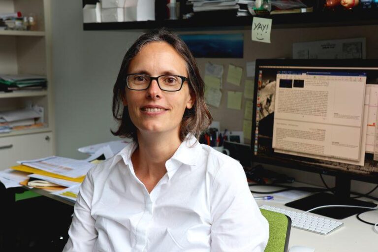Image of Kat in the workplace, smiling at camera, for obituary.